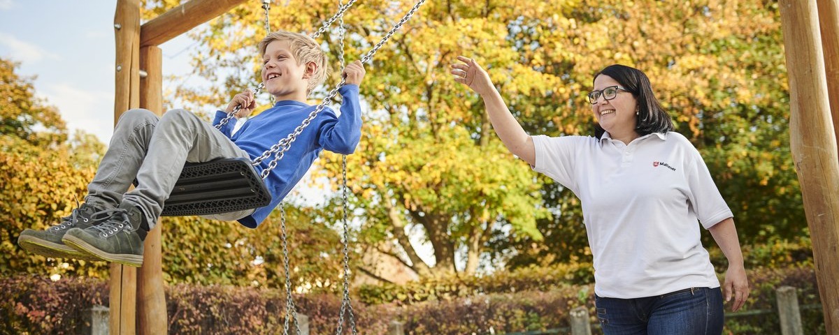 Mitarbeiterin schaukelt mit einem Kind