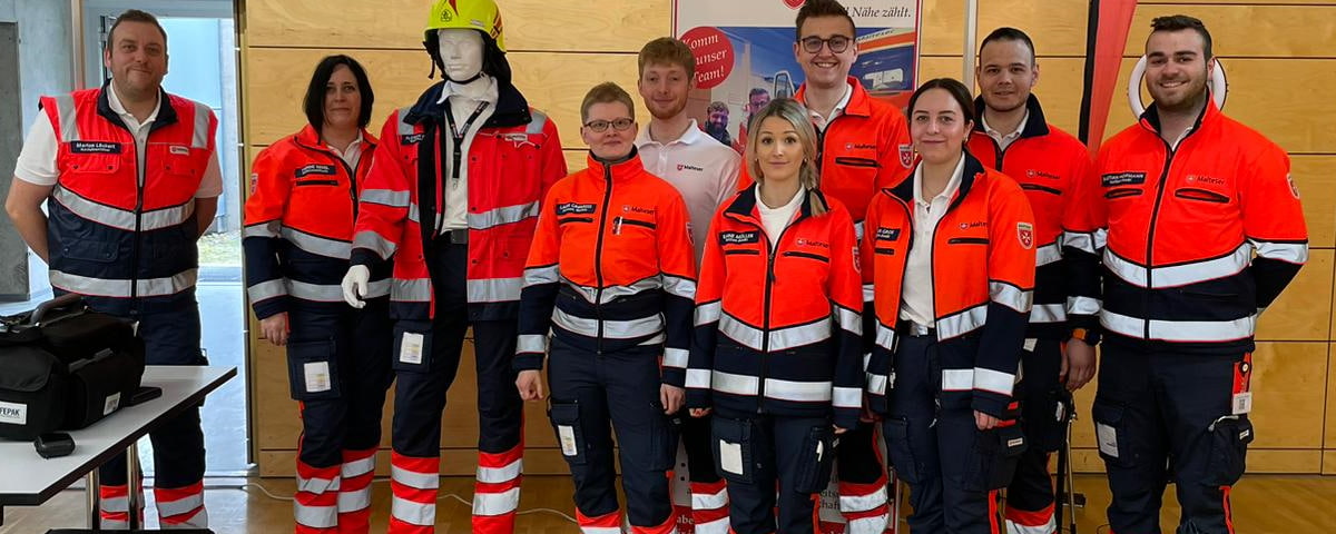 Team der Rettungswache von Rettungssanitätern und Notfallsanitätern steht zusammen und freut sich auf neue Mitarbeitende.