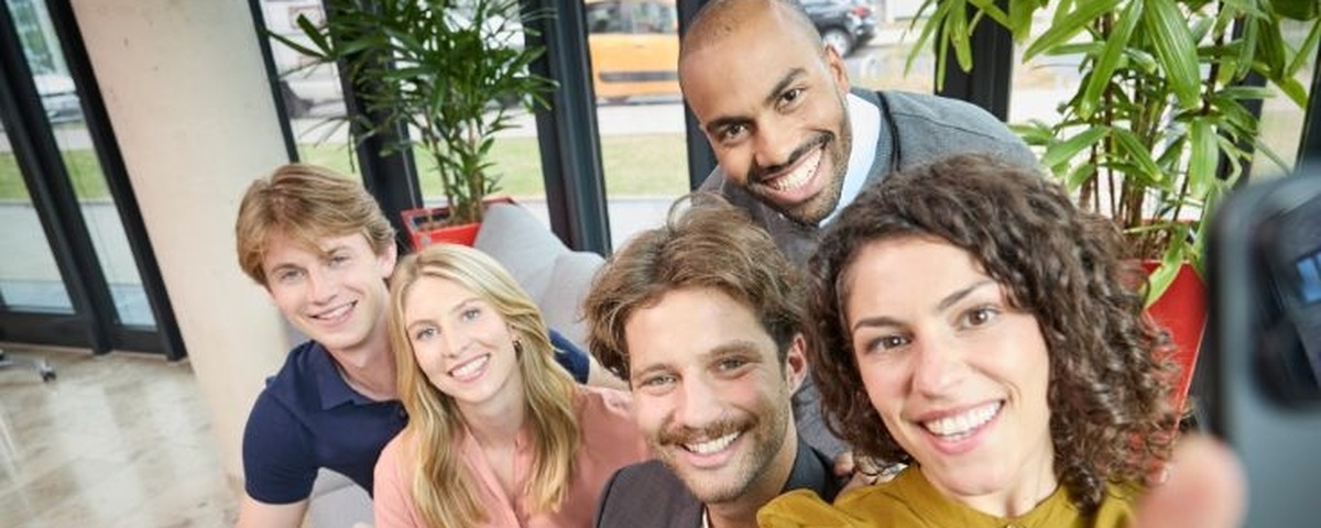 Mehrere Trainees lächeln gemeinsam ins Handy
