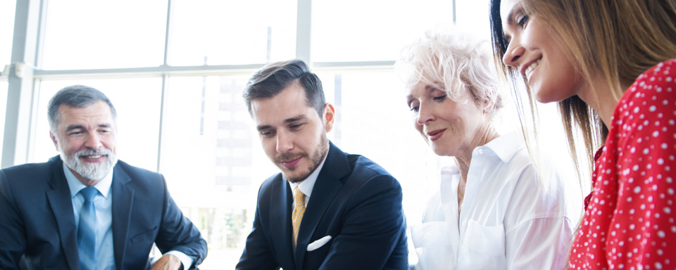 Vier Mitarbeiter vom Management der Malteser schauen sich gemeinsam etwas an.