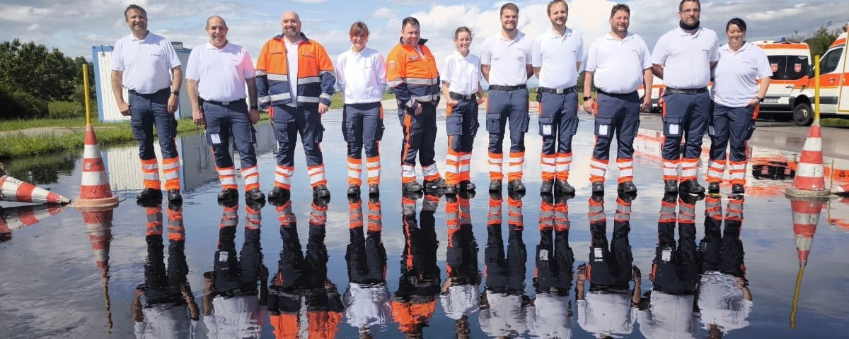 Das Team des Rettungsdient in Bayern steht zusammen und gucken gemeinsam in die Kamera.